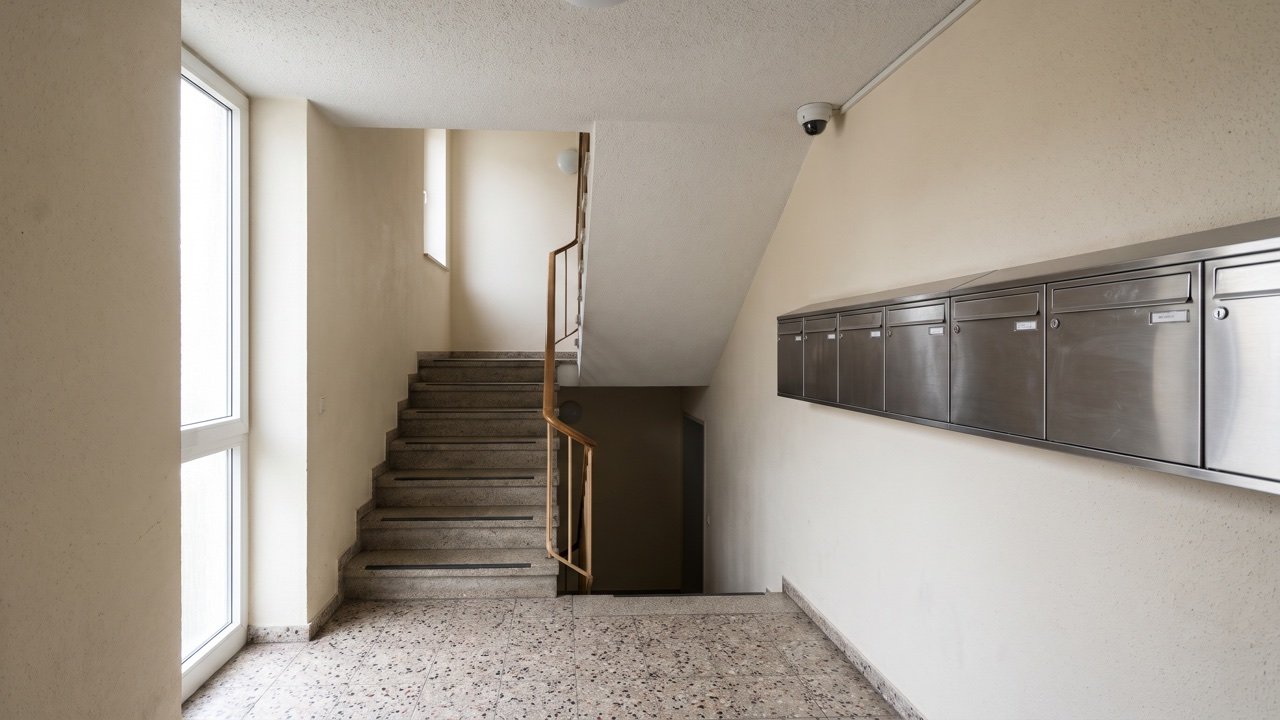 Treppenhaus eines Mehrfamilienhauses mit Dome-Kamera, die auf die Briefkästen und nicht auf die Wohnungstüren gerichtet ist