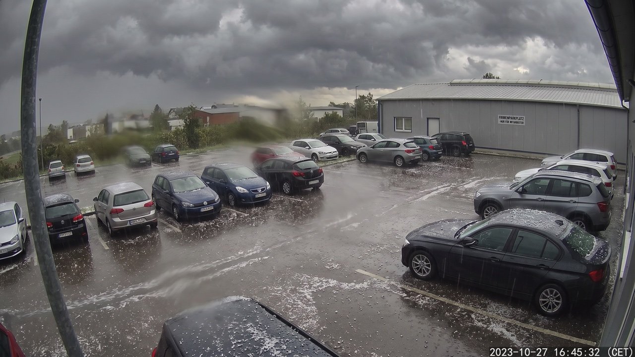 Parkplatz mit Autos während eines Hagelschauers